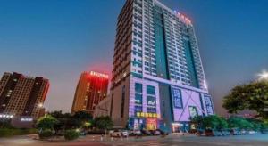 a tall building with neon lights in a city at Foshan Baolong Hotel in Nanzhuang