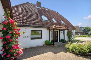 a white house with a brown roof and some flowers at Gartenwohnung in Westerdeichstrich