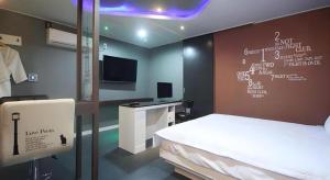 une chambre avec un lit et un bureau avec une télévision dans l'établissement Huen Hotel Gimhae, à Mugye-ri