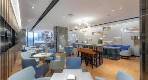 a restaurant with blue chairs and tables and a bar at Echarm Hotel Guilin North High Speed Railway Station in Guilin