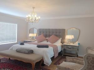 a bedroom with two beds and a chandelier at Bloubergstrand Beachfront Apartment Witsand 101 Tablemountain and ocean views in Cape Town