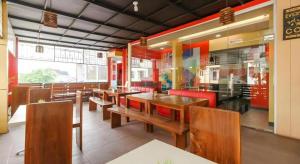a dining room with wooden tables and red chairs at Hotel JAV Front One in Lahat
