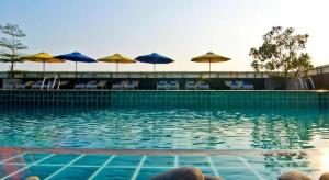 a swimming pool with chairs and umbrellas at Rashmi's Plaza Hotel Vientiane in Ban Souanmon