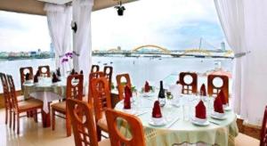a dining room with a table and a view of the water at Bamboo Green Hotel in Da Nang