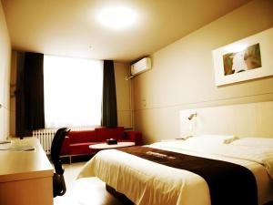 FuxinにあるJinjiang Inn Fuxin Yinbin Street Branchのベッドと赤いソファのあるホテルの部屋 +11枚の写真