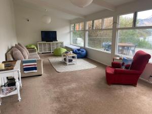 a living room with a couch and a red chair at Beachfront Tranquility in Tikao Bay in Wainui