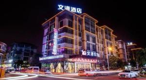 a building with a sign on top of it at night at mingjia hotel in Yiwu