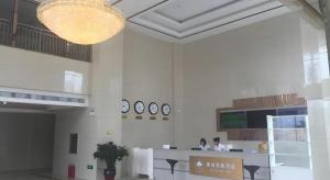 a lobby with a counter and clocks on the wall at GreenTree Inn Tangshan Xueyuan Road Business Hotel in Fujiatun