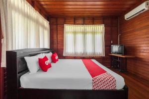 - une chambre avec un lit doté d'oreillers rouges et une télévision dans l'établissement OYO 1143 Phet Luran Thai Resort Kohchang, à Ko Chang