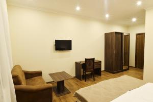 a living room with a tv and a chair and a table at MGK Hotel in Tbilisi City