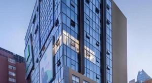 a tall glass building with the sun shining on it at ibis Styles Kunming Nanping Hotel in Kunming