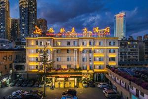 un grand bâtiment avec des voitures garées dans un parking dans l'établissement GreenTree Inn Kunming Baiyun Road Tongde Plaza Branch, à Kunming