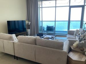Una sala de estar con un sofá y un televisor de pantalla plana. en 2BR Beachfront Apartment with Ocean Views, en Ajman
