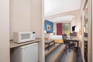 a hotel room with a bed and a desk with a microwave at Baymont By Wyndham Laurel in Laurel