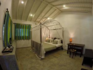 a bedroom with a canopy bed and a desk at The Horizon Hill Top Villa in Unawatuna