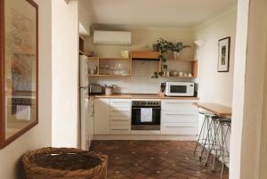 eine kleine Küche mit weißen Schränken und einer Mikrowelle in der Unterkunft Dennis Cottage Clare Valley in Auburn