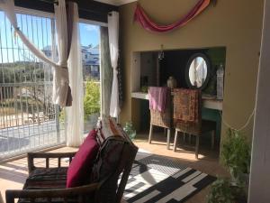 a living room with a couch and a table and window at 120 steps to the beach in Pringle Bay