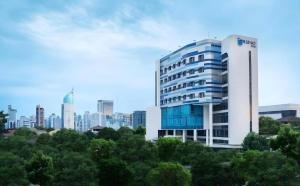 a tall white building with trees in front of a city at Blue Sky Hotel Petamburan in Jakarta