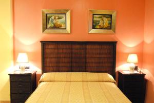 Hotel Pinomar في إل بويرتو دي سانتا ماريا: غرفة نوم مع سرير مع مواقف ليلتين وصورتين على الحائط