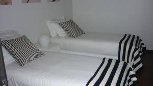 a white bed with black and white pillows on it at 12 Short Term in Porto