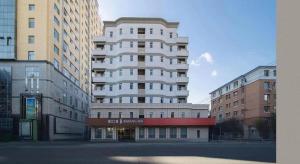 un grand bâtiment blanc dans une ville avec des bâtiments dans l'établissement Jinjiang Inn Changchun Xi An Avenue Branch, à Changchun