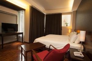 um quarto de hotel com uma cama, uma mesa e cadeiras em Baansilom Soi 3 em Bangkok