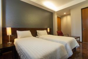 una habitación de hotel con dos camas y una silla en Baansilom Soi 3, en Bangkok