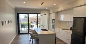 a kitchen with white cabinets and a counter with chairs at Beach House Perth in Perth