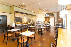 a restaurant with tables and chairs in a cafeteria at Hotel AreaOne Miyazaki City in Beppuchō