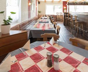 a row of tables in a restaurant with red and white table cloth at Pension Altes Backhaus in Herzogenaurach