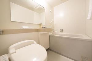 a white bathroom with a toilet and a bath tub at Kamikochi Taishoike Hotel in Matsumoto +156 photos