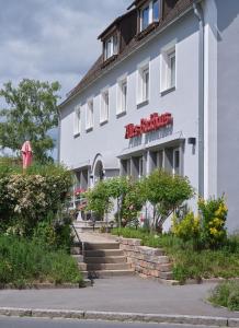 a white building with a red sign on it at Pension Altes Backhaus in Herzogenaurach