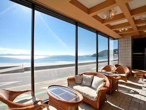 a balcony with chairs and tables and large windows at Shinojima Royal Hotel Kasuisou in Minamichita