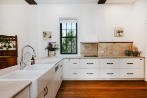 une cuisine avec des armoires blanches et un évier dans l'établissement The Warehouse - Heritage Elegance in Central Mudgee, à Mudgee 132 autres photos