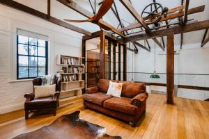 un salon avec un canapé et une chaise dans l'établissement The Warehouse - Heritage Elegance in Central Mudgee, à Mudgee