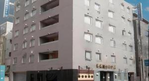 un grand bâtiment blanc dans une rue de la ville dans l'établissement Niigata Keihin Hotel, à Nuttari