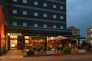 a restaurant with tables and umbrellas in front of a building at APA Hotel Tsukuba Bampaku Kinenkoen Ekimae in Tsukuba