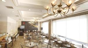 a restaurant with tables and chairs and a chandelier at Kamisuwa Station Hotel in Suwa