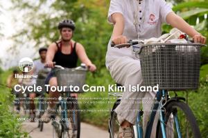 a woman riding a bike with a man in the background at Hoianese Trainquil Heritage Hotel - A Member Of Hoianese Cultural Experiential Hotel in Hoi An