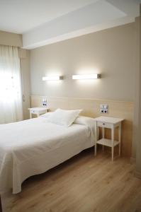 1 Schlafzimmer mit einem weißen Bett und 2 Tischen in der Unterkunft Hotel Alaiz in Beriáin