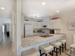 a kitchen with white cabinets and a counter with stools at Sweet Location with Sophistication in Tybee Island