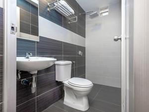 a bathroom with a toilet and a sink at Hotel Aromas Kulai in Kulai