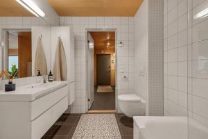 a white bathroom with a toilet and a sink at Northstay - House of Northern Lights in Tromsø +24 photos