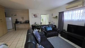 a living room with a leather couch and a television at Opal's Rest in Nelspruit