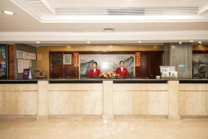 two people standing behind a bar in a restaurant at Shunde Emperor Hotel in Shunde