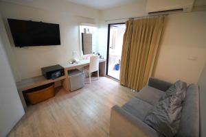 ein Wohnzimmer mit einer Couch und einem Schreibtisch mit einem Fernseher in der Unterkunft Sawasdee House in Bangkok