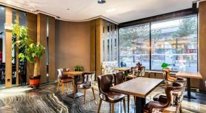 a restaurant with tables and chairs and a large window at Zmax Hotel·Harbin Bingxue Big World in Harbin