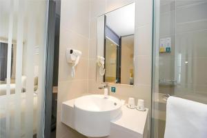 une salle de bain blanche avec un lavabo et une douche dans l'établissement City Comfort Inn Chengdu Longquanyi District Beijing Road, à Chengdu