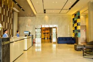 Echarm Hotel Xiantao Yuantai Weilaicheng في Xiantao: ردهة مبنى مكاتب مع رجل يقف عند المنضدة