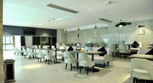 合肥市にあるEcharm Hotel Hefei Binhu Exhibition Centerの白い椅子とテーブルとテーブルと椅子のあるレストラン